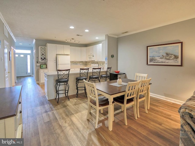 dining space with light wood-type flooring and crown molding