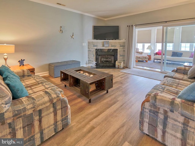 living room featuring a fireplace, crown molding, light hardwood / wood-style floors, and a wealth of natural light