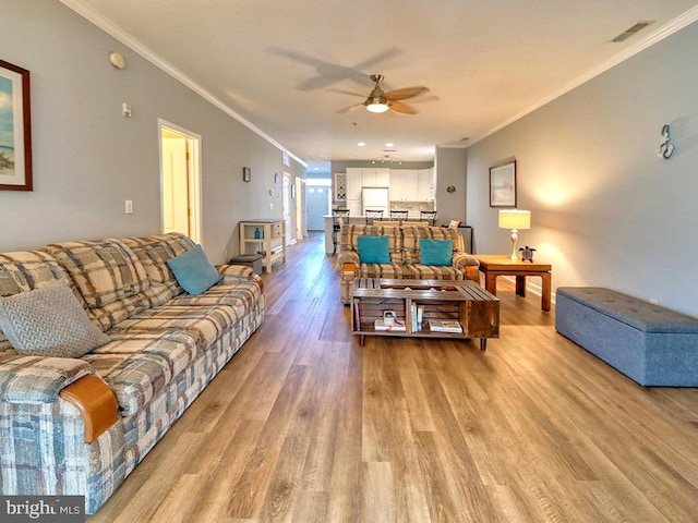 living room with crown molding, light hardwood / wood-style floors, and ceiling fan