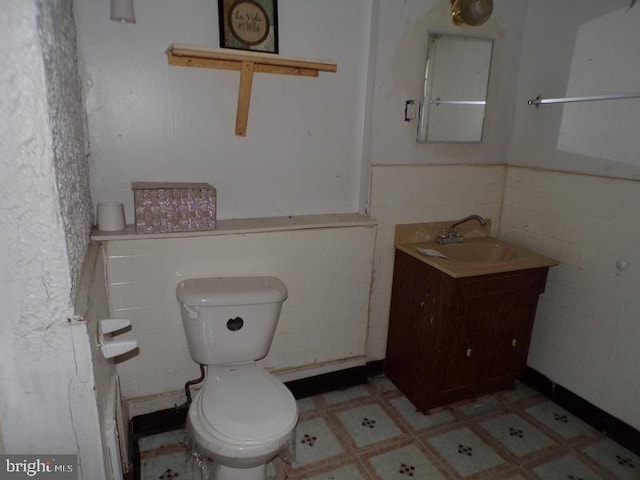 bathroom featuring vanity, toilet, and tile walls