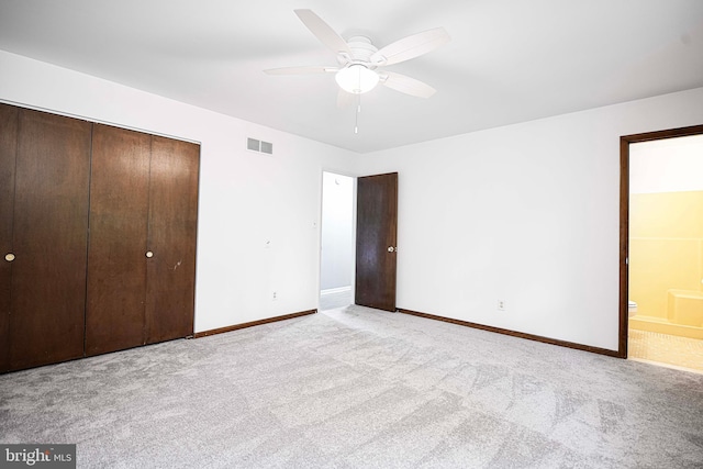 unfurnished bedroom with ceiling fan, ensuite bath, light carpet, and a closet