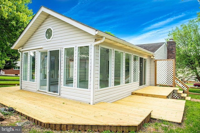 view of property exterior featuring a sunroom and a deck