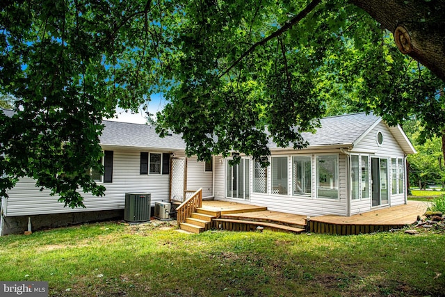 back of property with central AC, a deck, a sunroom, and a lawn