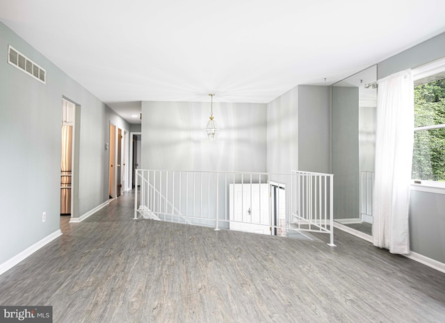 empty room with a notable chandelier and dark hardwood / wood-style flooring