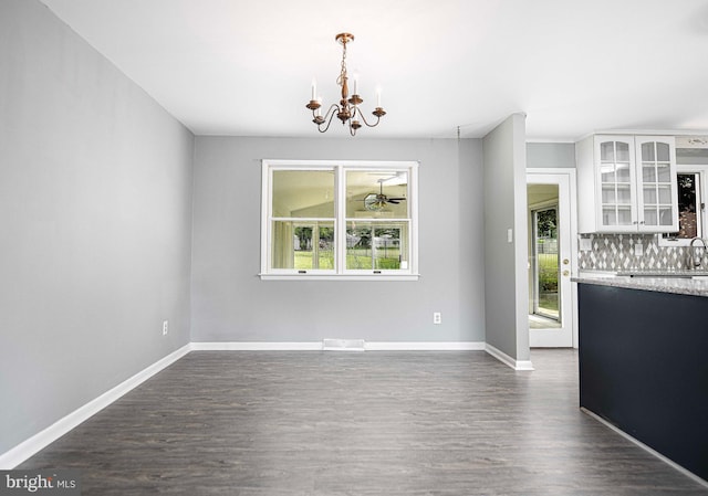 unfurnished dining area with a healthy amount of sunlight, dark hardwood / wood-style floors, and a notable chandelier