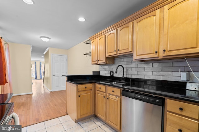 kitchen with backsplash, dark stone counters, sink, appliances with stainless steel finishes, and light hardwood / wood-style floors