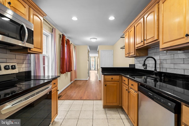 kitchen with sink, light tile patterned flooring, dark stone counters, and appliances with stainless steel finishes