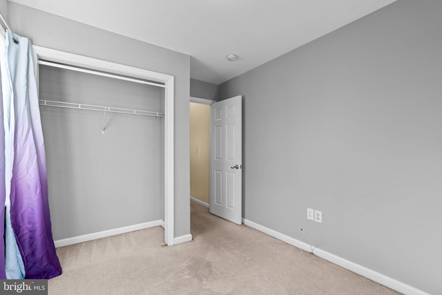 unfurnished bedroom with a closet and light colored carpet