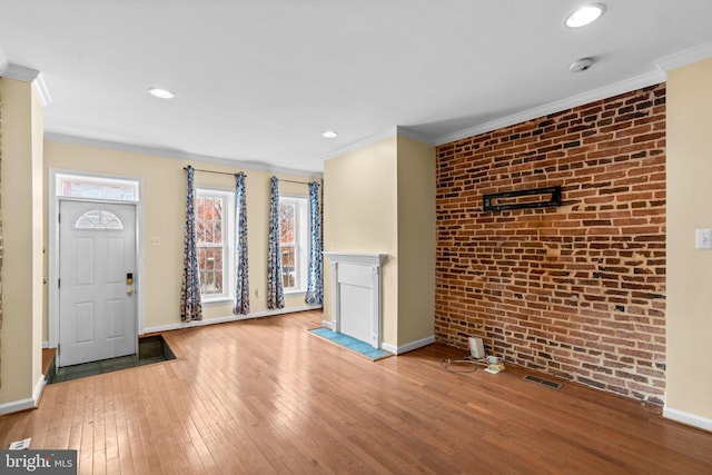 unfurnished living room with light hardwood / wood-style floors, crown molding, and brick wall