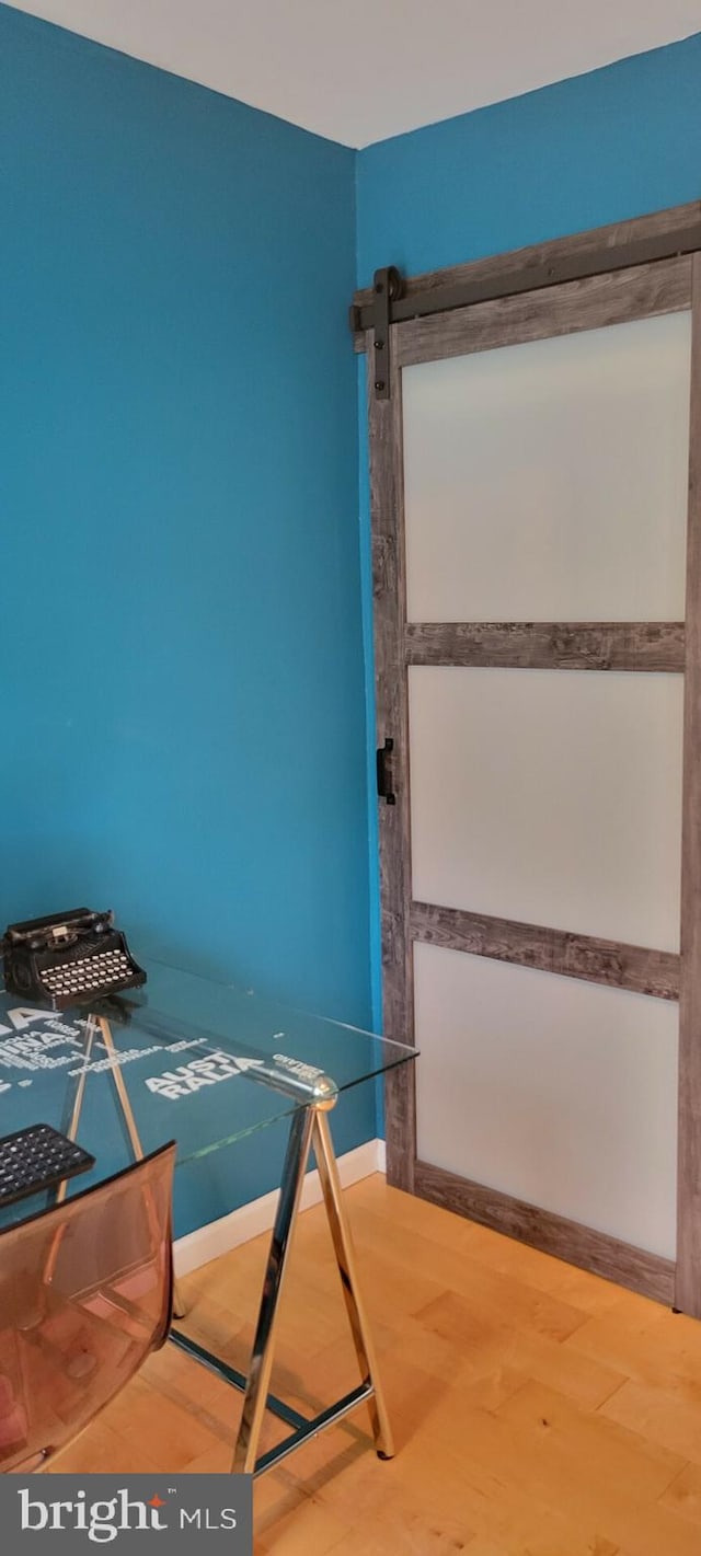 unfurnished bedroom with wood-type flooring and a barn door