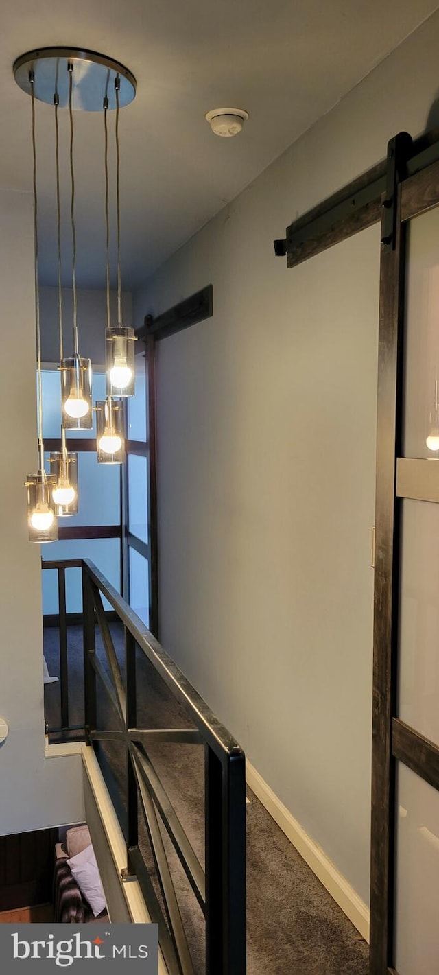 stairs with a barn door and carpet floors