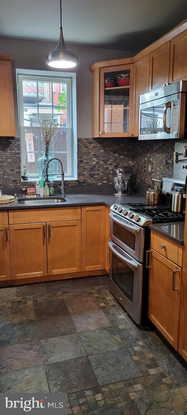 kitchen featuring decorative backsplash, sink, stainless steel appliances, and decorative light fixtures