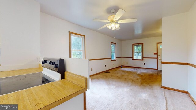 interior space with ceiling fan, plenty of natural light, white electric range, and light carpet