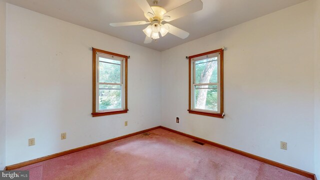 carpeted empty room with a wealth of natural light and ceiling fan