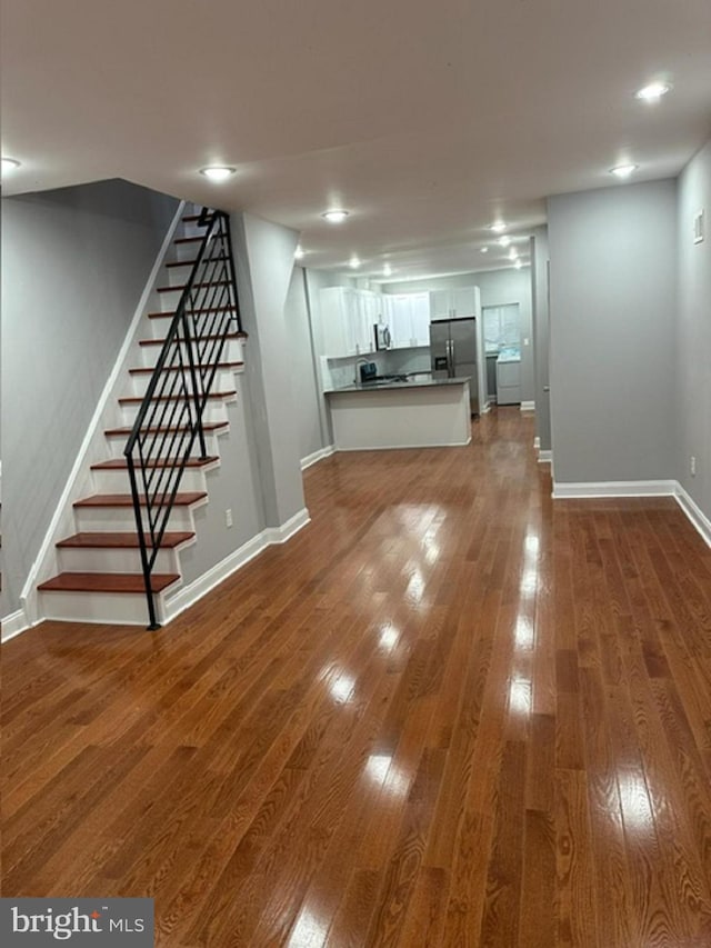 basement with hardwood / wood-style floors and stainless steel refrigerator with ice dispenser