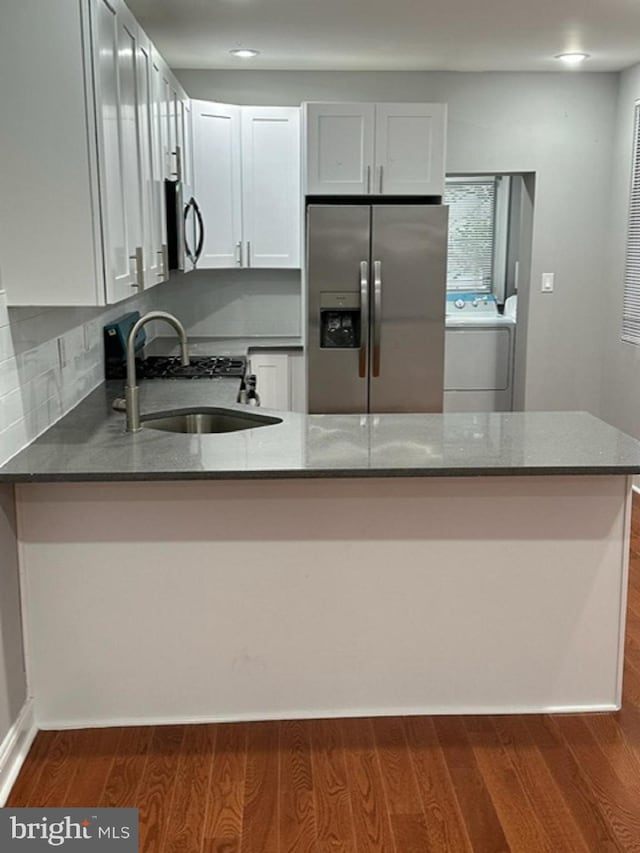 kitchen with white cabinets, washer / clothes dryer, kitchen peninsula, and stainless steel appliances