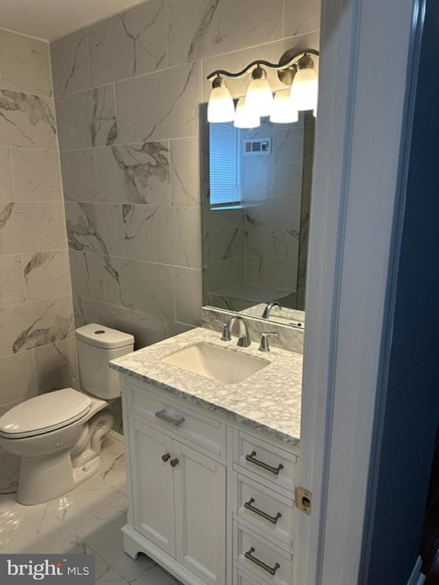 bathroom with tile patterned flooring, tile walls, toilet, and vanity