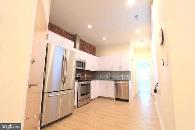 kitchen featuring sink, appliances with stainless steel finishes, light hardwood / wood-style floors, tasteful backsplash, and white cabinets