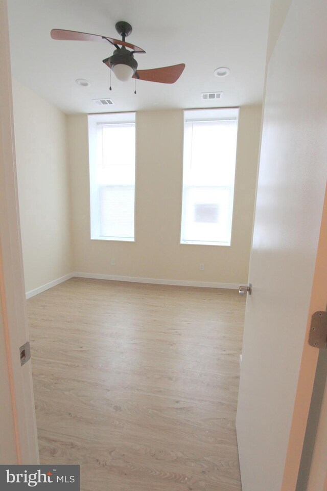 empty room featuring ceiling fan, plenty of natural light, and light hardwood / wood-style floors