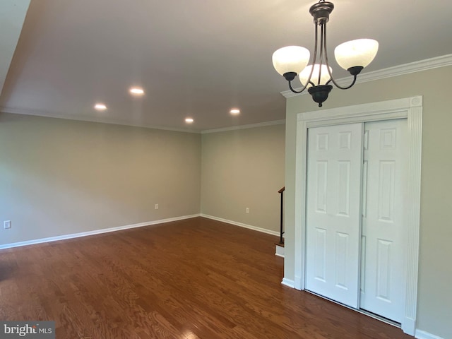 spare room featuring an inviting chandelier, dark hardwood / wood-style floors, and crown molding