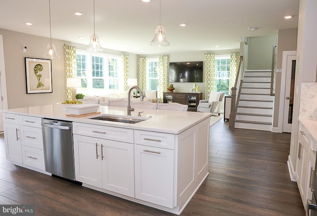 kitchen featuring dark hardwood / wood-style floors, pendant lighting, an island with sink, stainless steel dishwasher, and sink