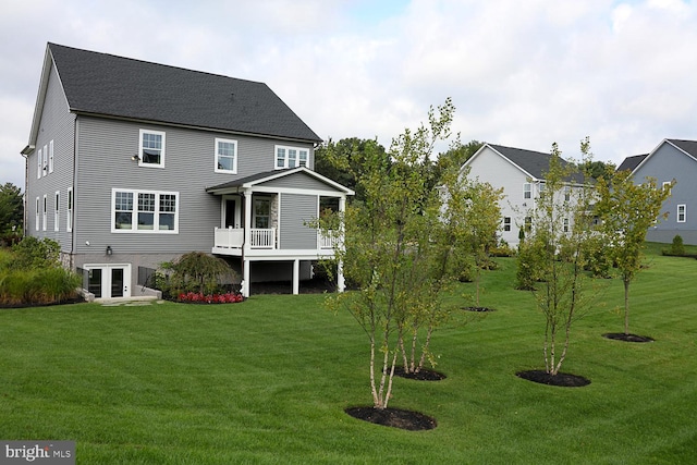 back of property featuring a balcony, french doors, and a yard