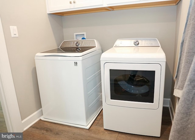 washroom with cabinets, wood-type flooring, and washing machine and dryer