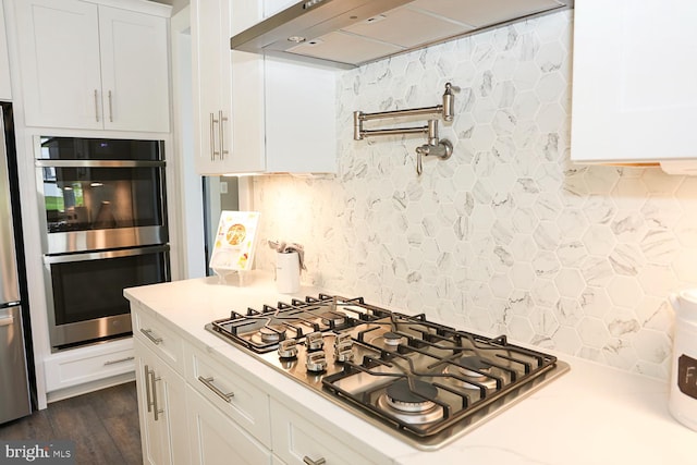 kitchen featuring dark hardwood / wood-style flooring, range hood, appliances with stainless steel finishes, and white cabinets