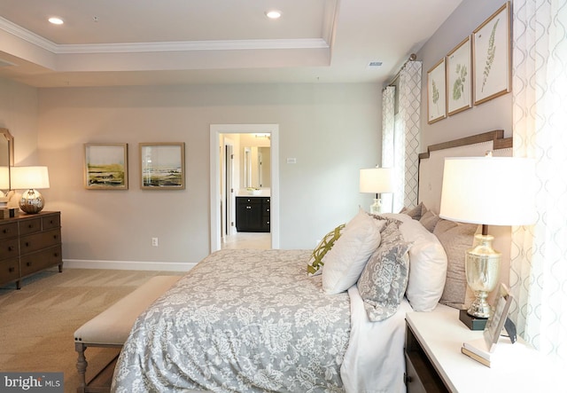 carpeted bedroom featuring crown molding, a raised ceiling, and ensuite bath