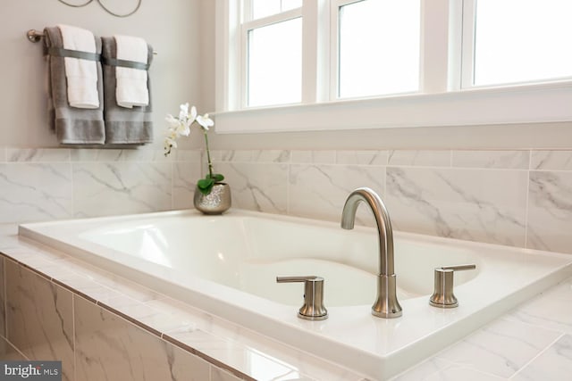 bathroom featuring a wealth of natural light and tiled bath