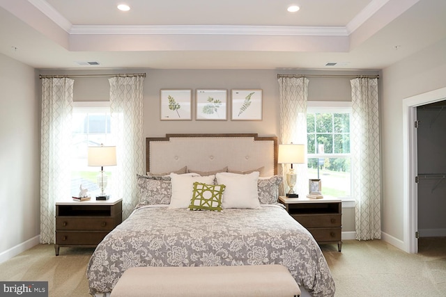 carpeted bedroom with a walk in closet, a tray ceiling, and crown molding