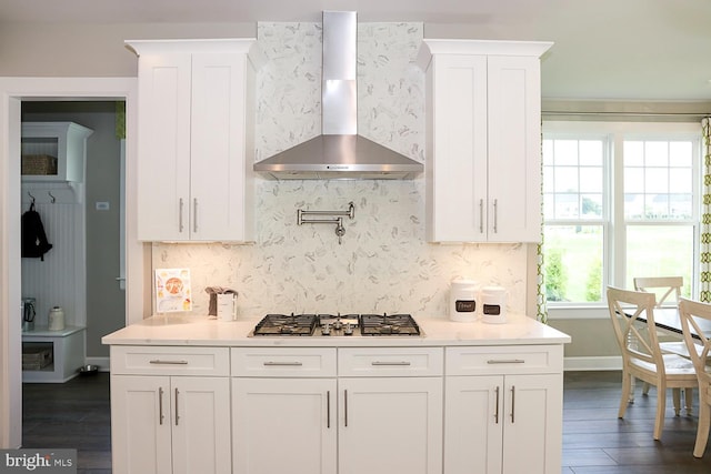 kitchen with wall chimney exhaust hood, dark hardwood / wood-style flooring, stainless steel gas stovetop, and white cabinets