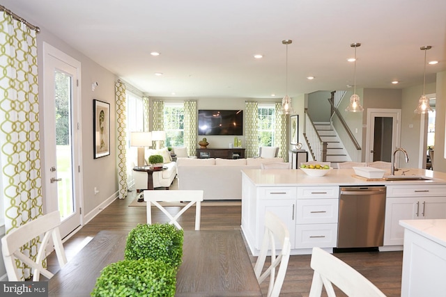 kitchen with white cabinetry, decorative light fixtures, dark hardwood / wood-style flooring, sink, and stainless steel dishwasher