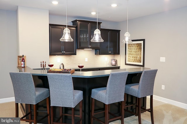 kitchen featuring hanging light fixtures, light colored carpet, kitchen peninsula, a breakfast bar area, and tasteful backsplash