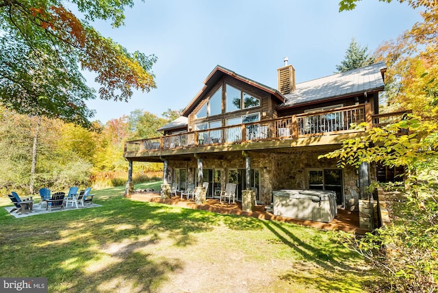 back of property with a hot tub, a patio, and a yard