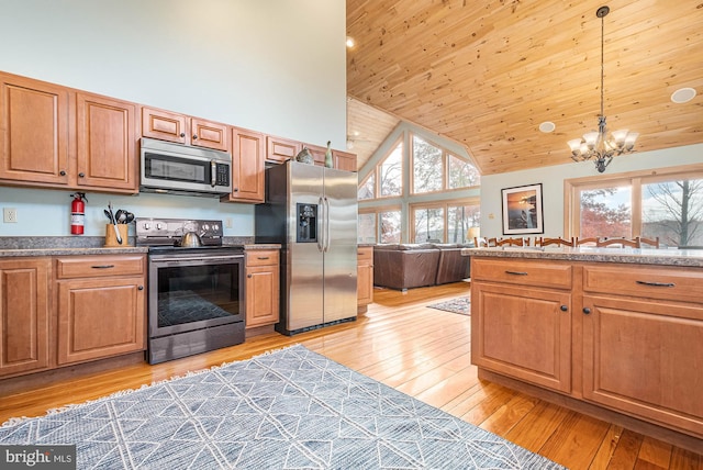 kitchen with a chandelier, appliances with stainless steel finishes, hanging light fixtures, high vaulted ceiling, and light hardwood / wood-style floors