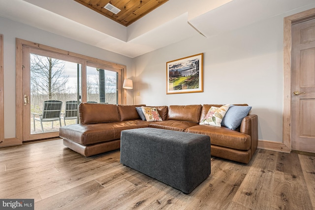 living room with light wood-type flooring, a wealth of natural light, a raised ceiling, and wood ceiling