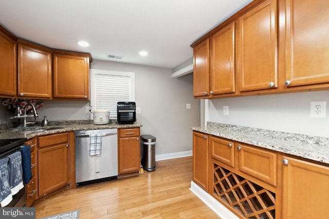 kitchen featuring light wood-type flooring, sink, dishwasher, and light stone counters