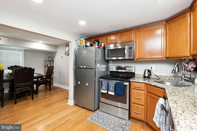 kitchen featuring appliances with stainless steel finishes, sink, and light hardwood / wood-style floors