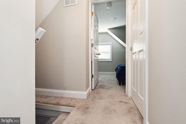 hallway featuring lofted ceiling and light colored carpet