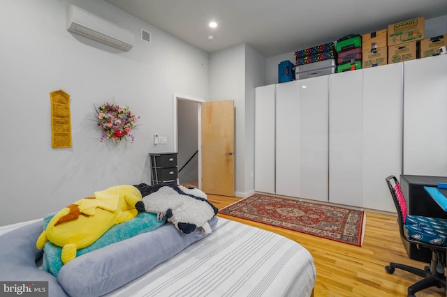 bedroom featuring light wood-type flooring and an AC wall unit