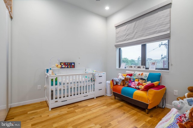 bedroom featuring light wood-type flooring and a crib