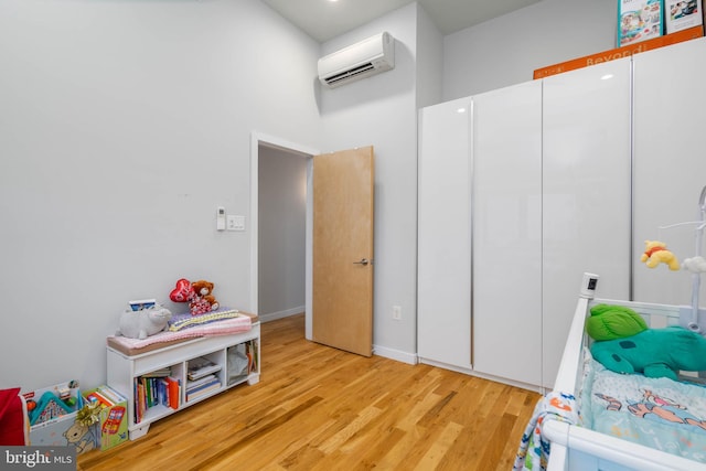 bedroom featuring an AC wall unit and light hardwood / wood-style flooring