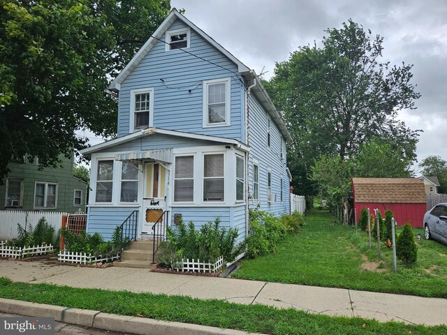 view of front of property with a front yard and a shed