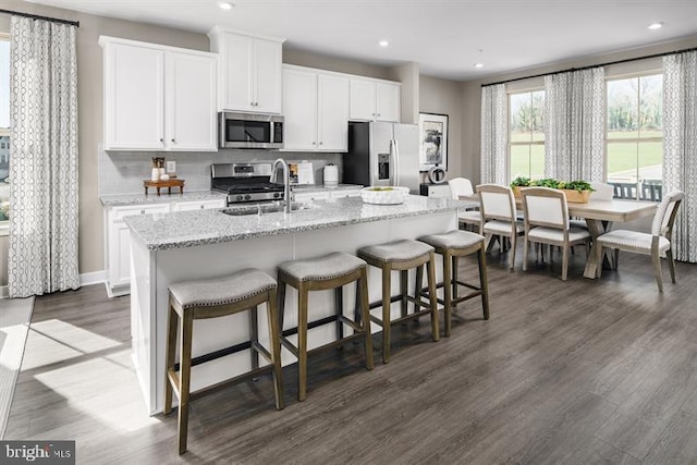 kitchen featuring appliances with stainless steel finishes, sink, white cabinetry, and a center island with sink