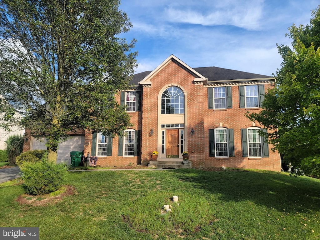 view of front facade featuring a garage, brick siding, and a front yard