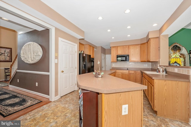 kitchen with black appliances, a kitchen island, sink, decorative backsplash, and light brown cabinets