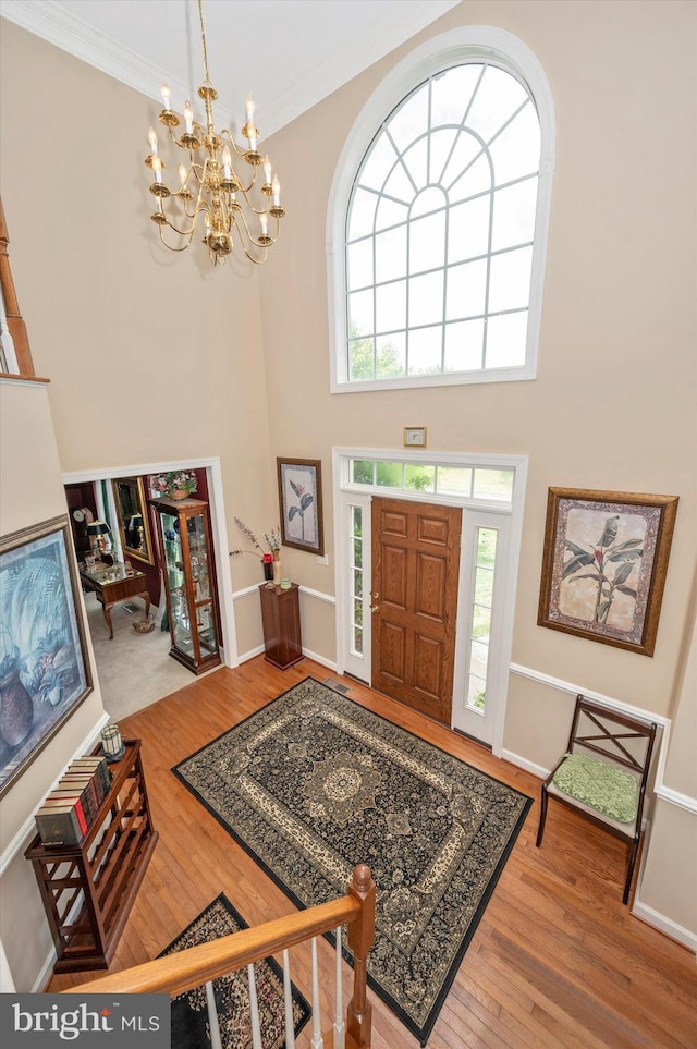 foyer entrance with hardwood / wood-style flooring, an inviting chandelier, and ornamental molding