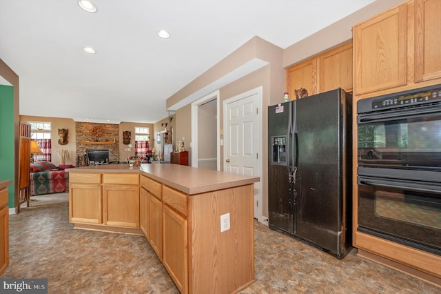 kitchen featuring a kitchen island, black appliances, light brown cabinets, and a fireplace