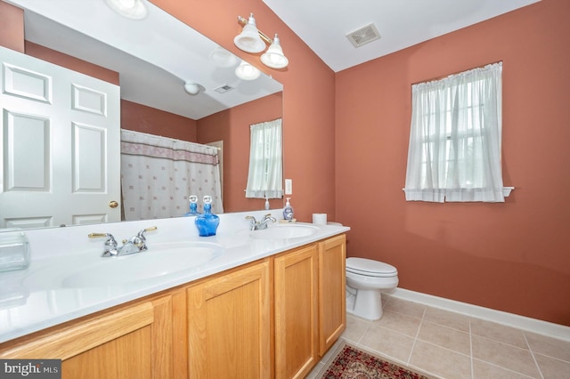 bathroom with vanity, toilet, a wealth of natural light, and tile patterned flooring